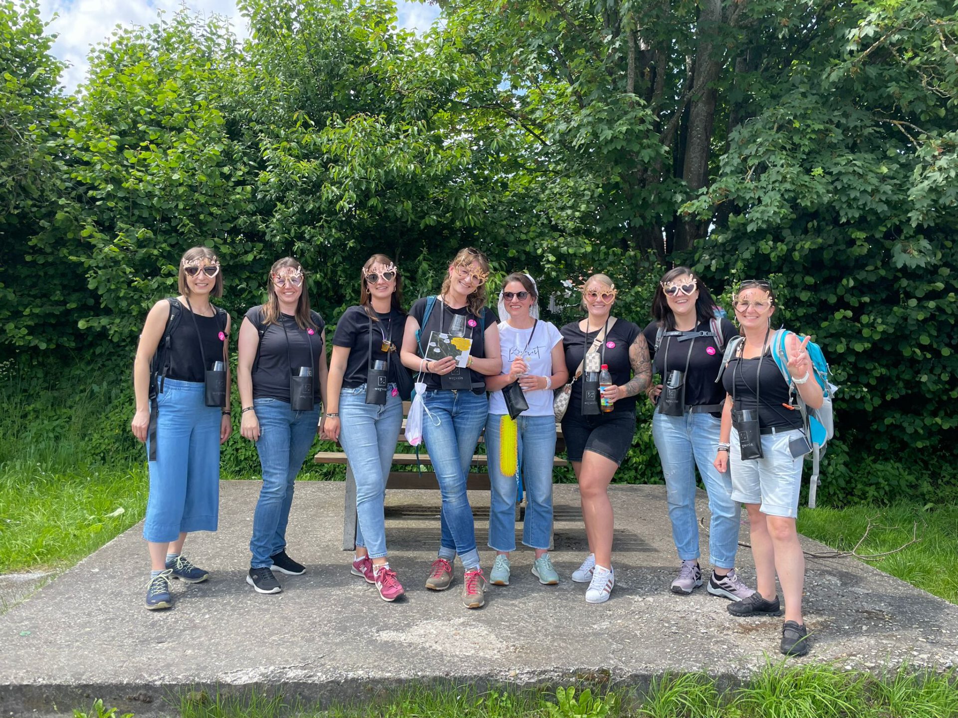 Weinwanderung: Gruppe mit Weingläsern auf Waldweg.